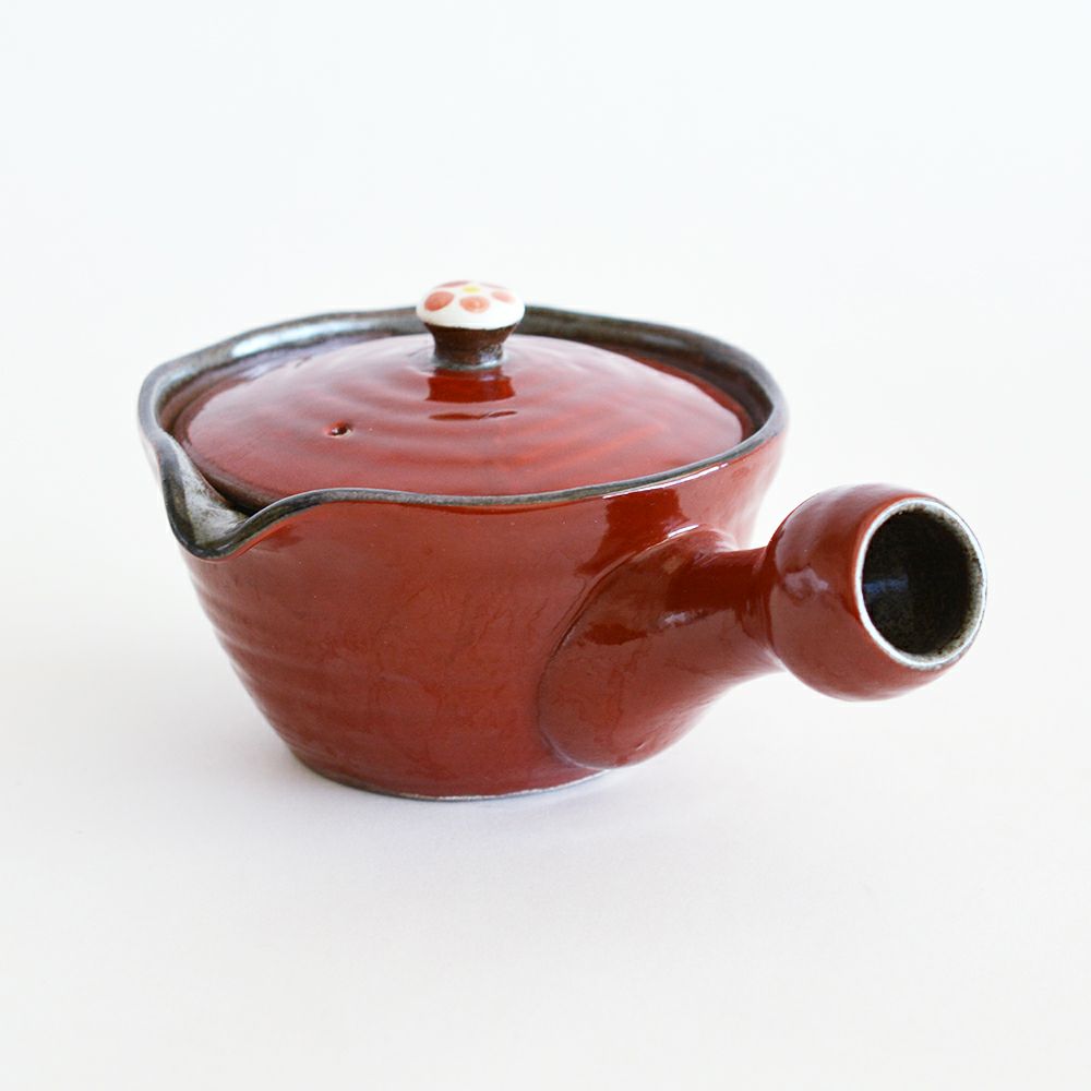 鮮やかな濃い赤色の釉薬と蓋にあしらわれたワンポイントの小梅模様が可愛らしい。ひとつとして同じもののない趣のある魅力的な濃（だみ）技法が施された赤濃小梅大急須